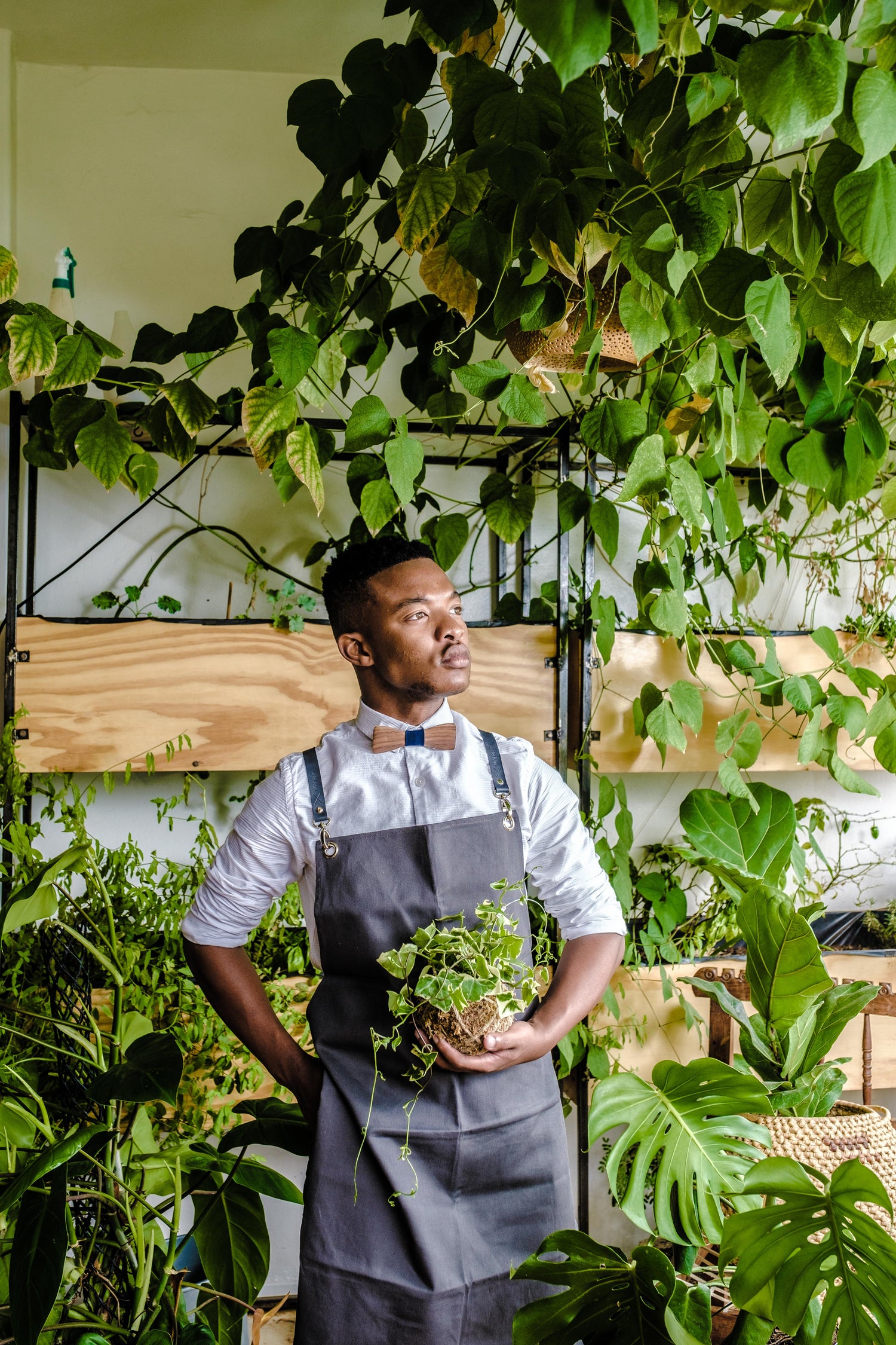 Man with charcoal apron standing in front of plants.