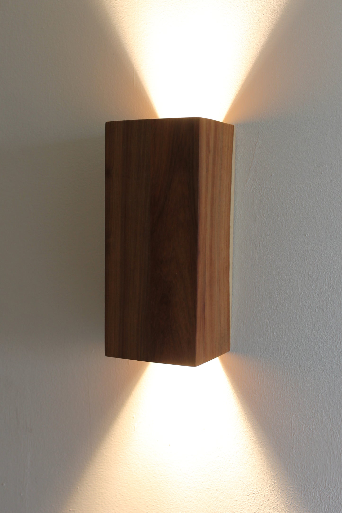 Wooden Up Down Wall Light illuminated in a dark room side view