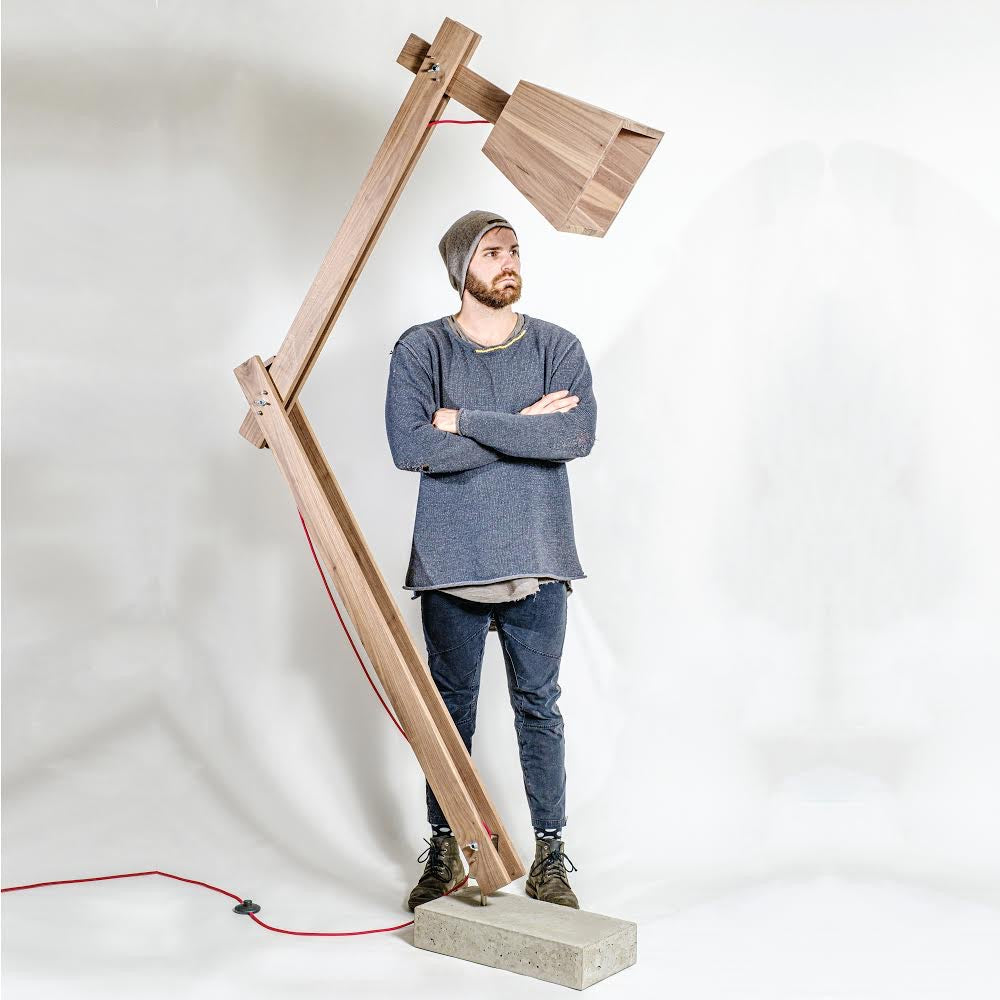 Walnut Timber and Concrete Floor Lamp displayed with the designer on a white background